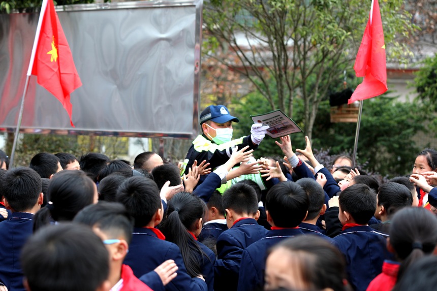 民警向學生發放交通安全宣傳單。