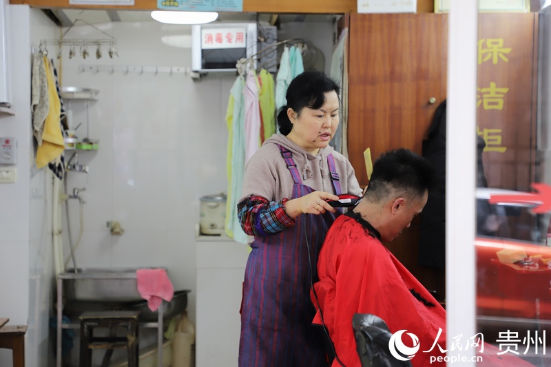“三八”婦女節當天，在貴陽市南明區一婦女正忙著為客人修理頭發。人民網 顧蘭雲攝