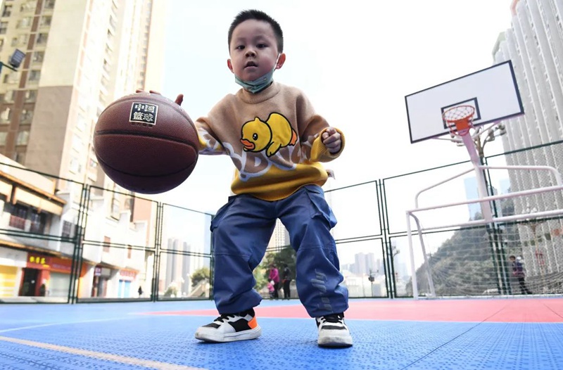 一名小朋友正在南明区小车河街道财富广场多功能球场锻炼身体。
