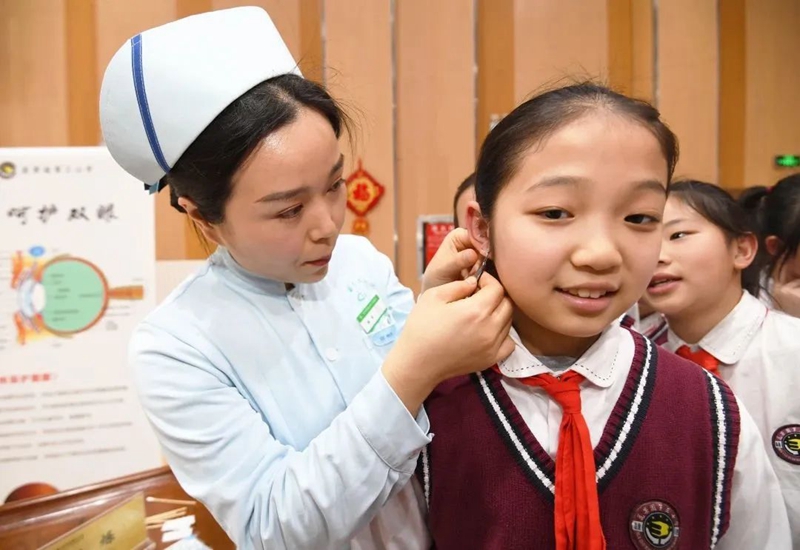 图片南明区花果园第三小学的一名学生正在中医药文化进校园活动现场体验耳穴埋豆治疗法2