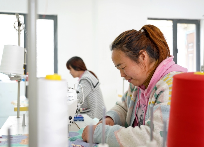 贵州省纳雍县珙桐街道白水河社区易地移民安置点的凯雄服饰有限公司生产车间里 ，工人正在加工围裙。
