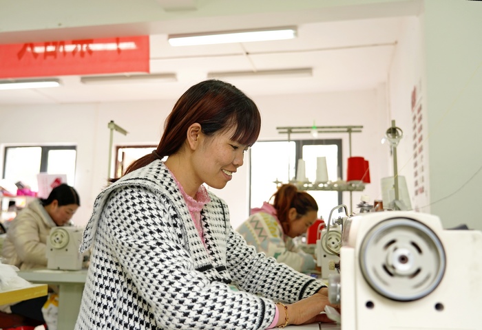 贵州省纳雍县珙桐街道白水河社区易地移民安置点的凯雄服饰有限公司生产车间里 ，工人正在加工围裙。