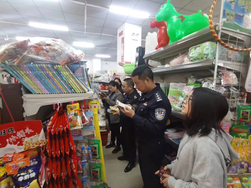 执法人员对乡镇百货超市所售书籍进行检查。
