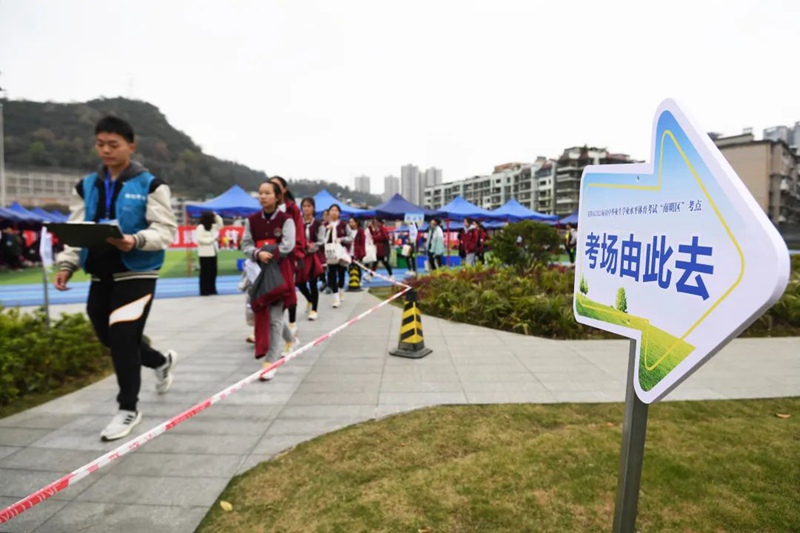 工作人员带领九年级学生前往立定跳远模拟测试现场。