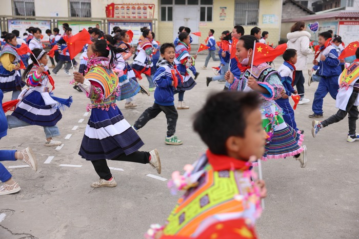 4月12日，贵州省纳雍县猪场乡新春村新寨小学，学生们正在挥舞着国旗跑操。