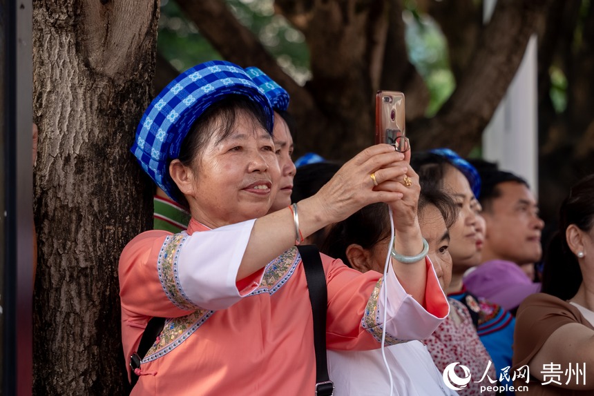 路邊圍觀的少數民族同胞用手機記錄巡游盛況。人民網記者 涂敏攝