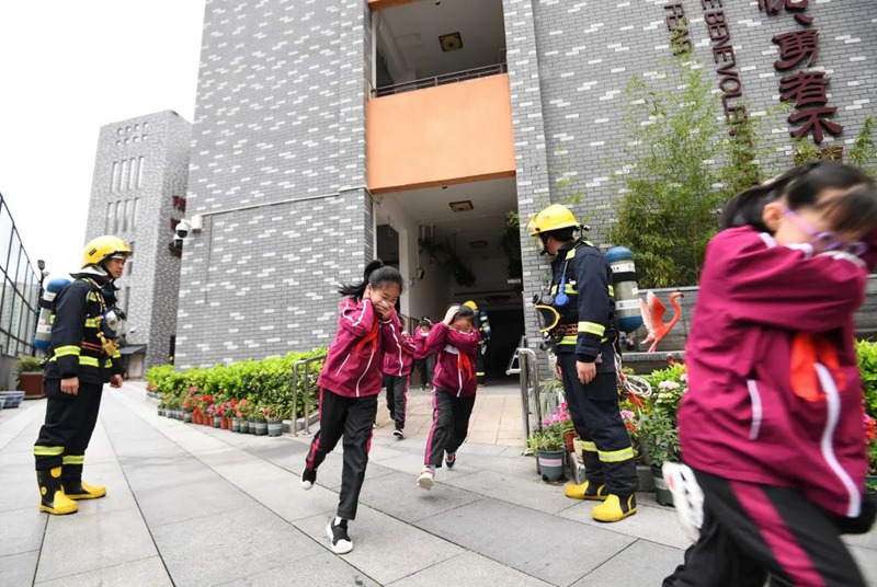学生正在花果园社区微型消防站专职消防员的引导下进行防震减灾应急疏散演练。