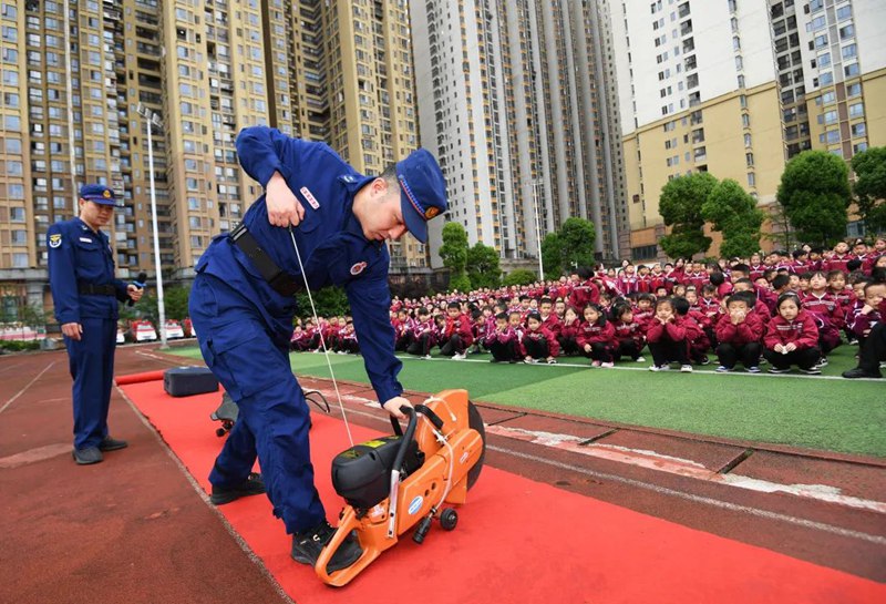 南明区花果园社区微型消防站的专职消防员正在给学生讲解消防救援装备的功能及使用方法。