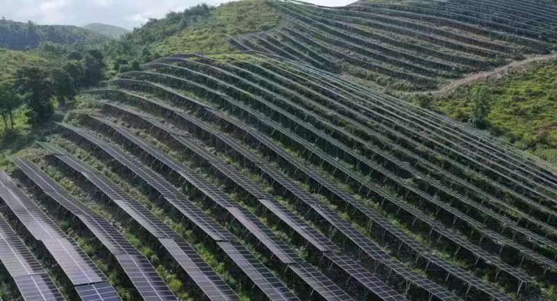 一片片光伏发电板整齐地陈列在青山之巅,守护着一方水土。