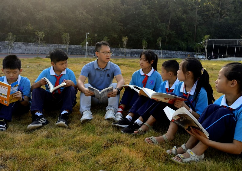 卢杨均与学生共阅读。