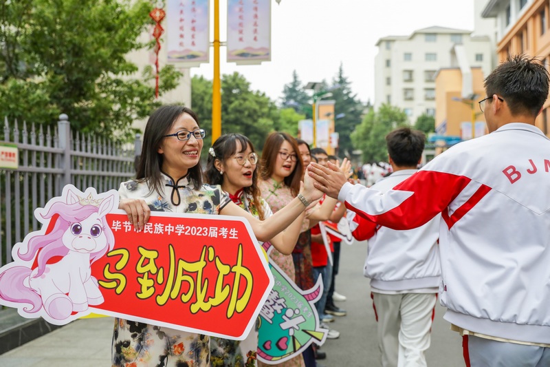 考生们携带准考证、身份证和考试必备文具从容赴考，家长们或穿红装、或举向日葵前来送考，为考生加油打气。胡秋婷摄