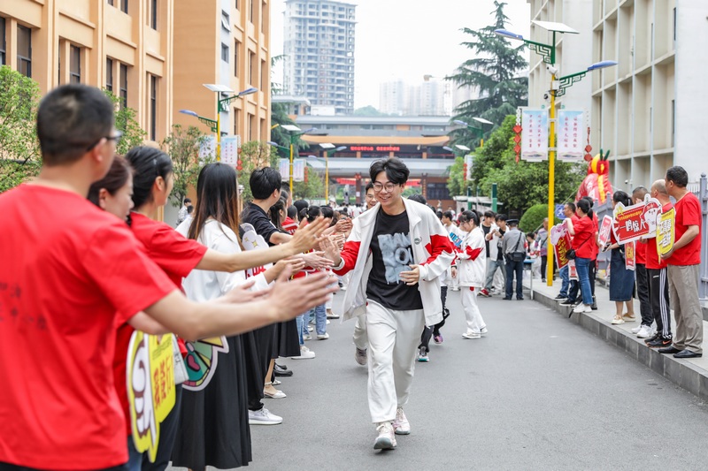 考生们携带准考证、身份证和考试必备文具从容赴考，家长们或穿红装、或举向日葵前来送考，为考生加油打气。胡秋婷摄