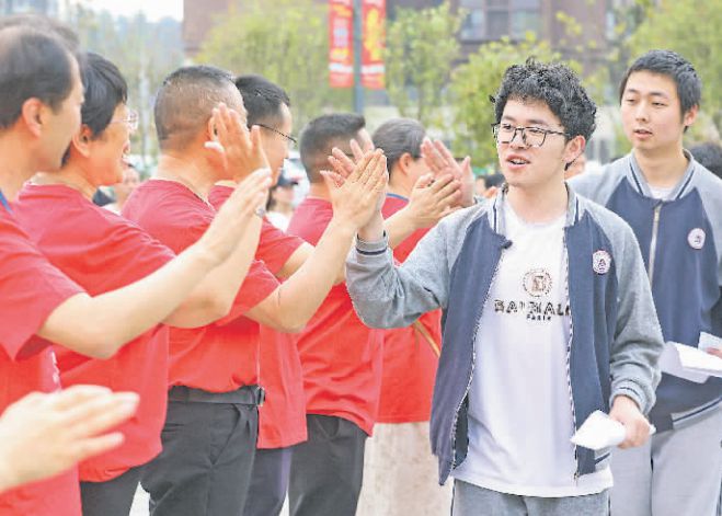 图为在北京师范大学贵安新区附属学校考点，送考老师排队与即将进入考点的考生击掌，为其加油鼓劲。石照昌摄