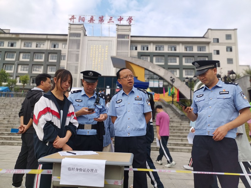 图为：开阳县第三中学考点，县公安局民警正在为考生协调办理临时身份证。