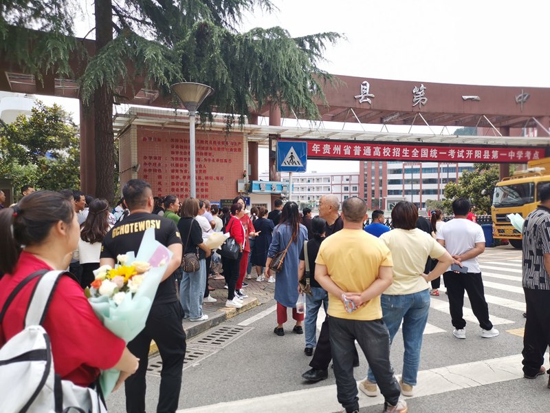 图为：开阳县第一中学考点，多名家长捧着鲜花等待考生出考场。