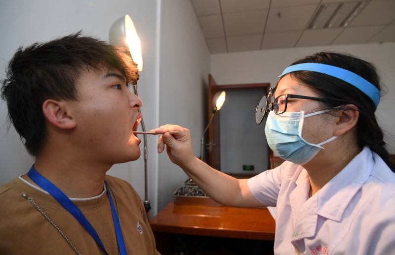 医护人员正在为应征青年进行口腔检查。