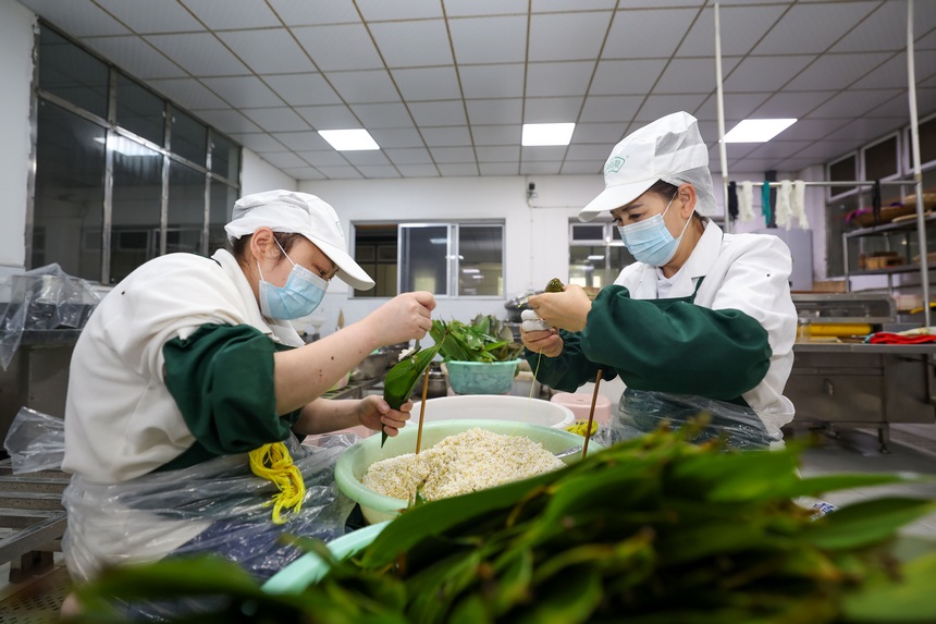 2023年6月19日，贵州省毕节市七星关经济开发区彝姑娘特色食品开发有限公司工人在包粽子。