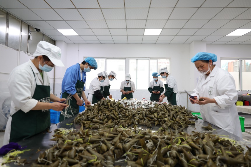 2023年6月19日，贵州省毕节市七星关经济开发区彝姑娘特色食品开发有限公司工人在检查粽子质量、包装粽子。