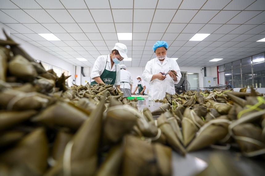 2023年6月19日，贵州省毕节市七星关经济开发区彝姑娘特色食品开发有限公司工人在检查粽子质量。
