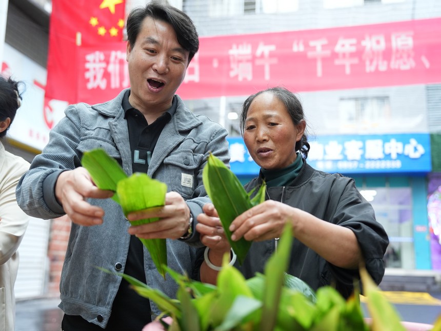 2023年6月21日大方縣紅旗街道包粽子比賽現場群眾學習包粽子。