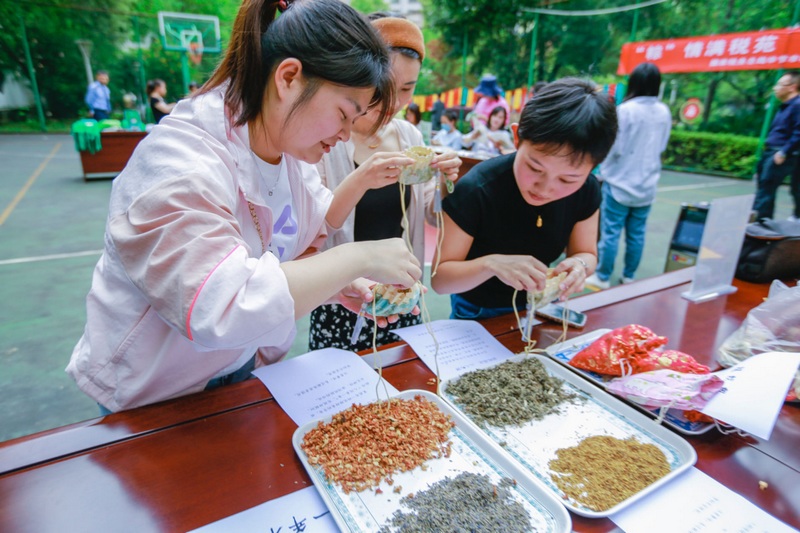 活动现场，税务干部职工正学习制作香囊。