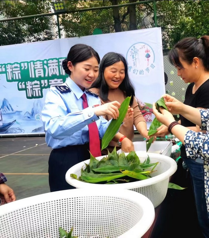 活动现场，税务局干部职工正在学习包粽子。