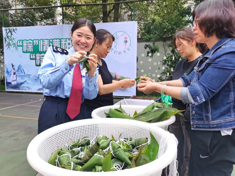 活动现场，税务局干部职工正在学习包粽子。