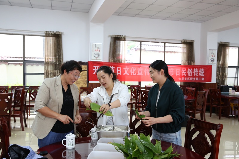 活动现场，志愿者正传授包粽子技巧。
