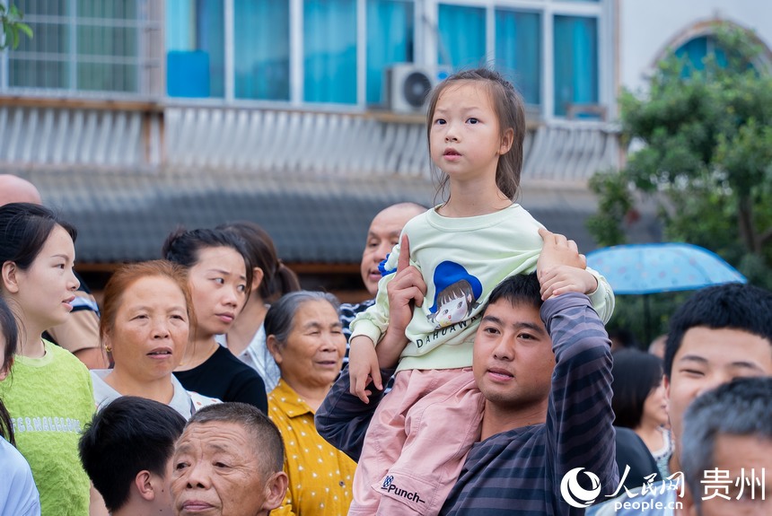 现场群众围观少数民族同胞巡游。人民网记者 涂敏摄