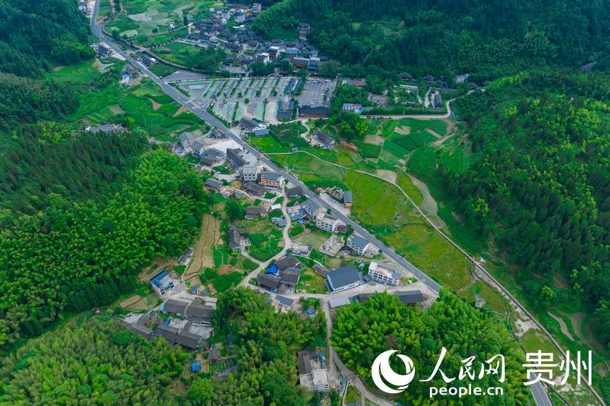 江口至梵净山环线公路旁的村庄与亚木沟景点大门。人民网记者 涂敏摄