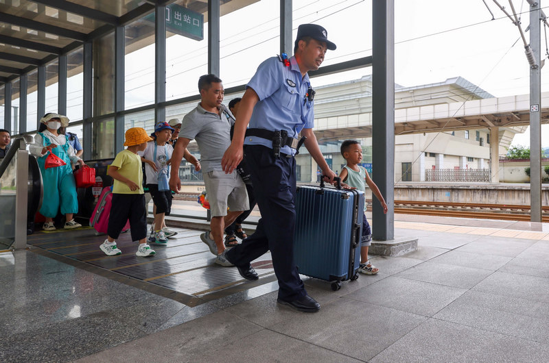 6月29日，铁路公安民警在沪昆高铁贵州铜仁南站帮助旅客搬运行李。