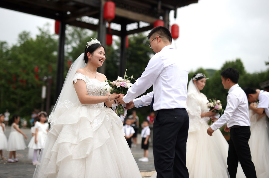 集體婚禮上，新郎給新娘獻花。 