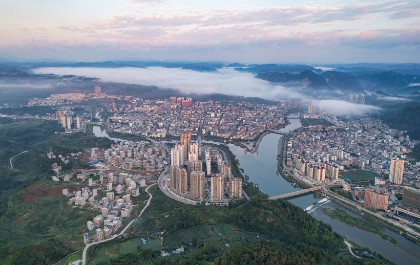 2023年7月10日，雨后的贵州省黔东南州施秉县城，远处的云雾与绿水青山、错落有致的建筑相映成景，构成了一幅秀美迷人的生态画卷。