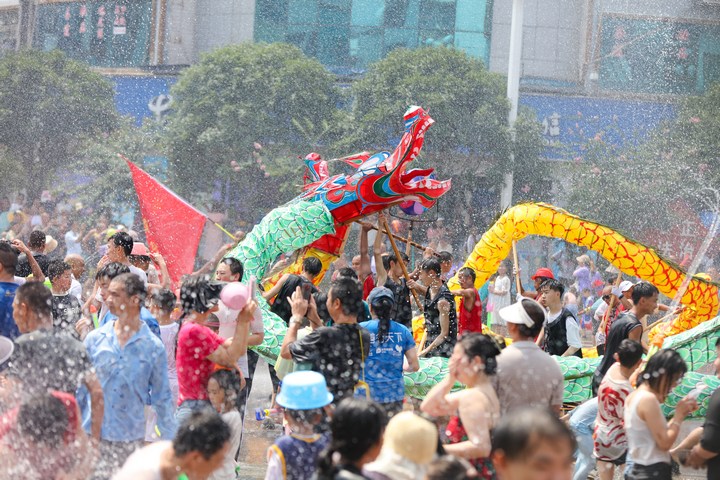 当地群众和游客在黔东南州施秉县玩水龙。