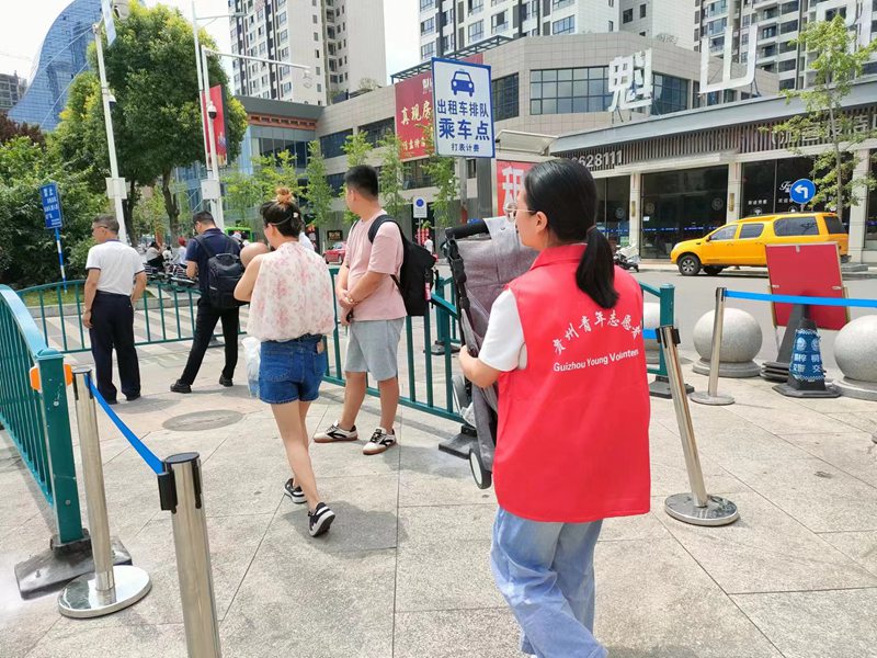 桐梓“小青椒”旅游志願者為游客搬運行李。