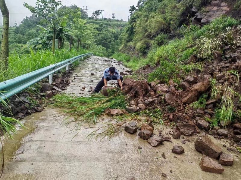 鸡场派出所冒雨徒手清理路面落石，消除道路安全隐患。