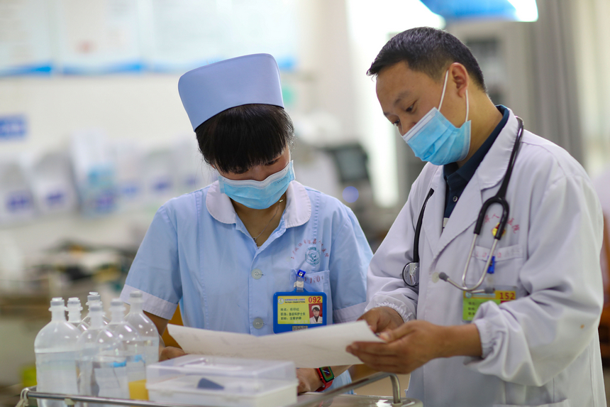 冉茂志（右）在玉屏侗族自治縣人民醫院急救科指導護士正確使用藥物（2021年5月9日攝）。