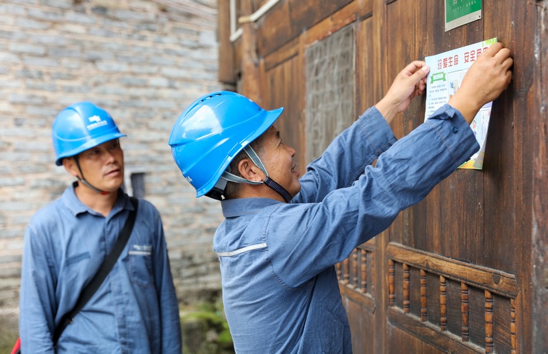 2023年9月5日，在贵州省黔东南州施秉县双井镇龙塘村，施秉供电局员工在张贴安全用电宣传画。