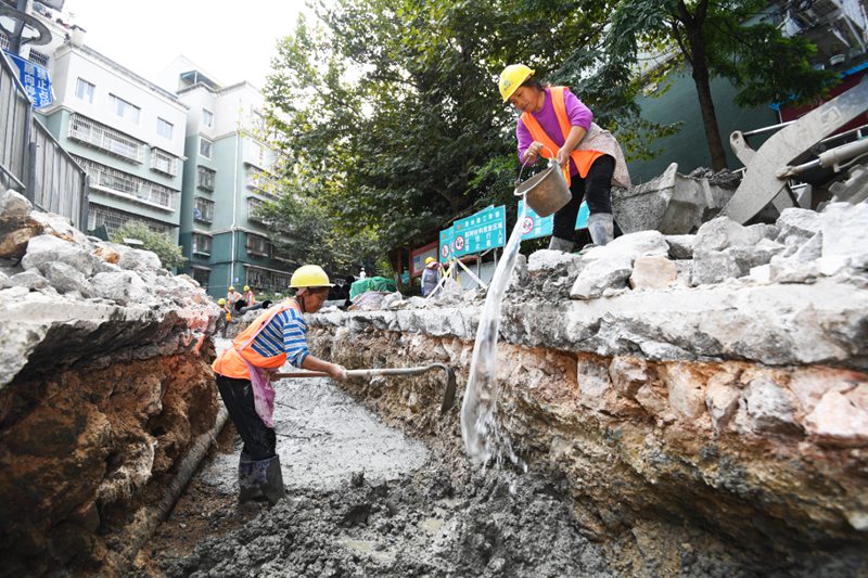 工人正实施排水管沟混泥土垫层作业。