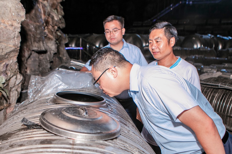 图3：邮储银行罗甸县支行工作人员查看刺梨发酵情况。