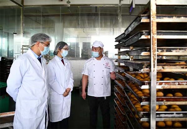 税务人员在威宁县一品鲜食品有限公司了解火腿月饼生产工艺，开展税收调研。张泉辉摄