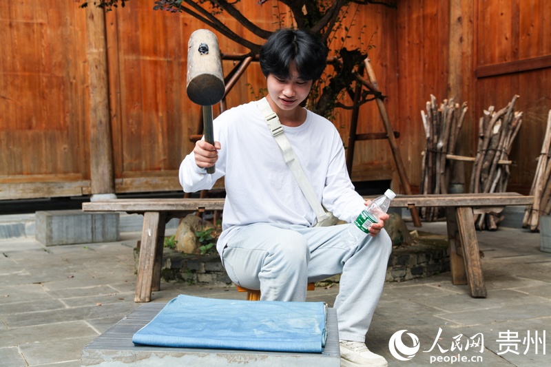 肇兴侗寨里，青年学生正在体验侗族服饰制作工序——锤布。人民网 王秀芳摄.jpg
