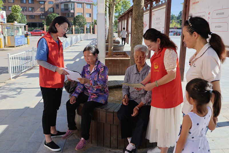 图为：志愿者给居民发放宣传资料，讲解治风相关知识