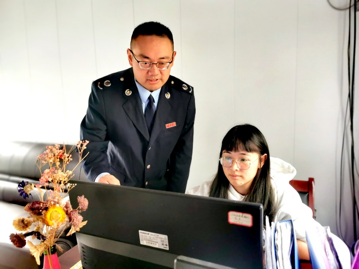 税务干部正在辅导公司财务人员进行网上申报。李艳摄