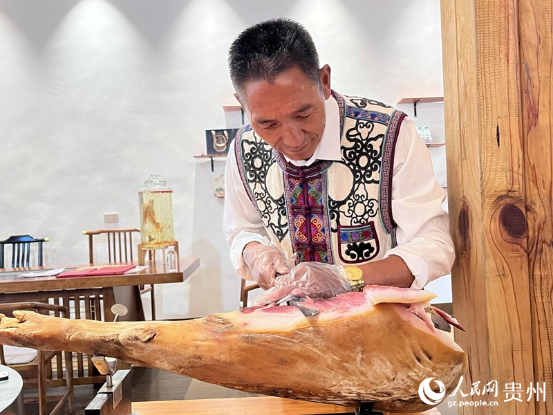 王福生正在切鲜火腿给游客品尝。人民网 陈洁泉摄
