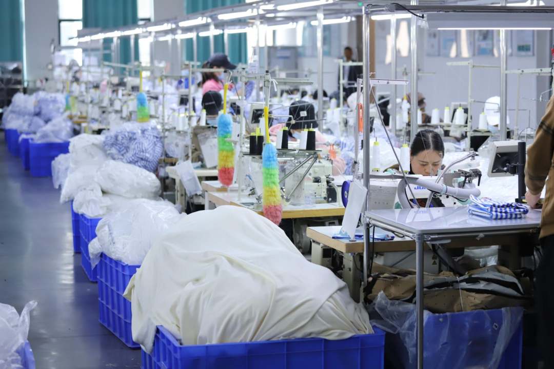  圖為工廠內工人縫制衣物，一派繁忙景象。