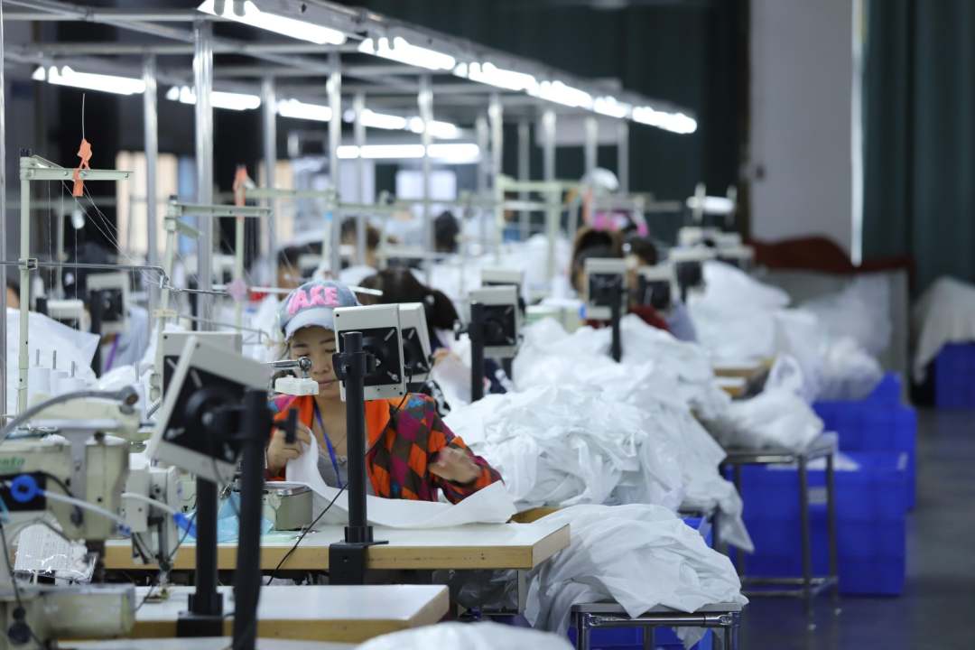  圖為工廠內工人縫制衣物，一派繁忙景象。