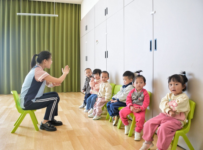 在仁人爱幼托育中心的教室里，来自成都师范大学毕业的姜姜老师正在较小朋友唱儿歌.jpg