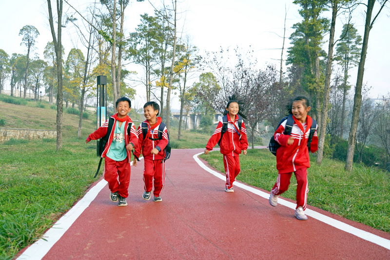 2023年11月17日,贵州省纳雍县白水河湿地公园,同学们在刚刚铺装的彩色沥青健身道上奔跑。 杨英摄