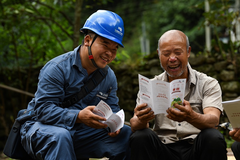 2023年6月26日，“天坑村”服务队为山洞组村民肖体友（右）宣传家居用电知识。